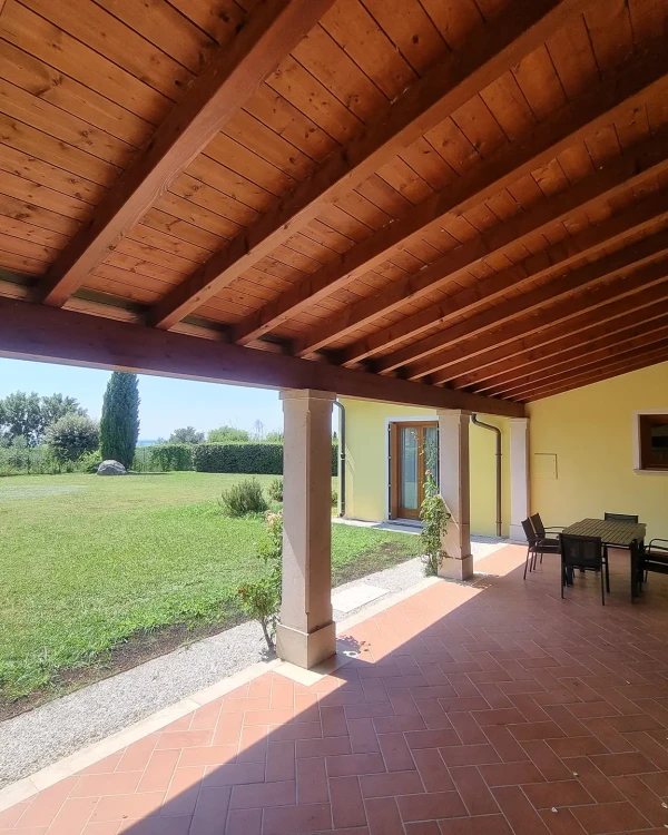 Portico con tetto in legno e vista su un ampio giardino verde.