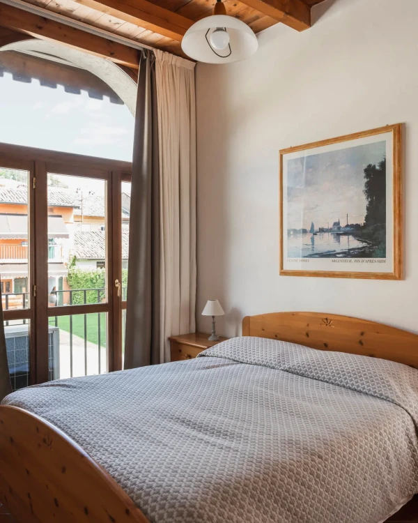 Camera da letto accogliente con letto matrimoniale, finestra luminosa e parete con quadro.