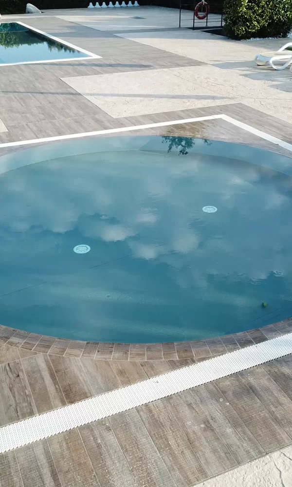 Vasca idromassaggio rotonda in un'area piscina con lettini.