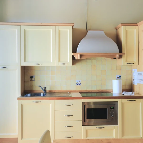 Cucina moderna con mobili color crema e forno a microonde integrato.