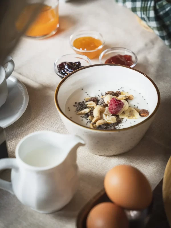 A breakfast spread with yogurt and fruit, jam, juice, milk, and eggs.