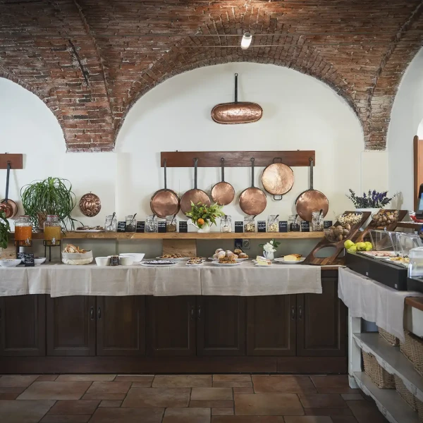 Buffet rustico in una sala con soffitto a volte e pentole di rame appese al muro.