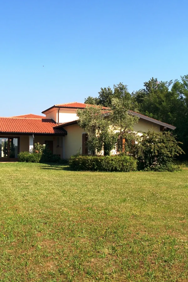 Casa singola con tetto in tegole rosse immersa nel verde.