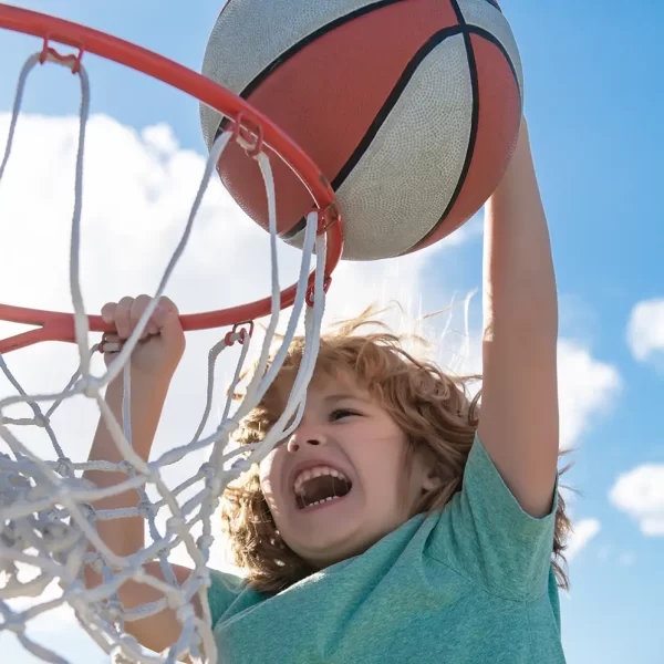 Ein Kind macht einen Basketball-Dunk vor einem blauen Himmel.