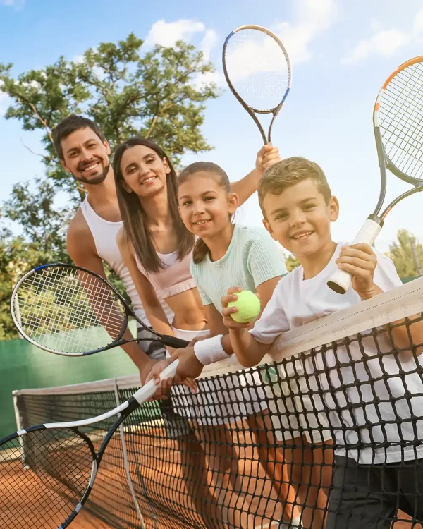 Famiglia felice che gioca a tennis su un campo all'aperto.