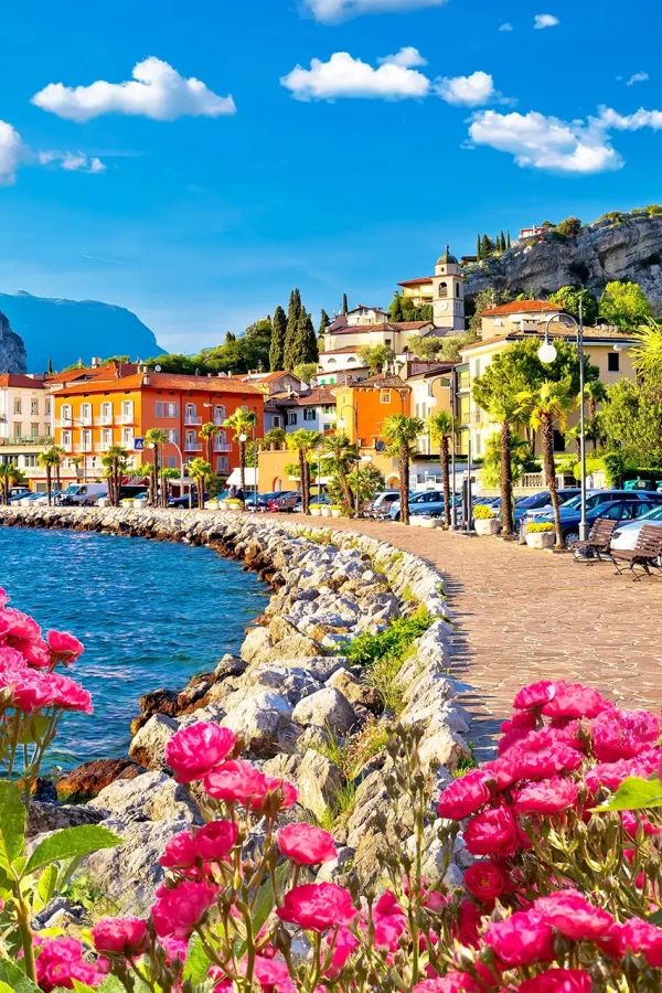 Colorful coastal town with vibrant flowers and mountains in the background.