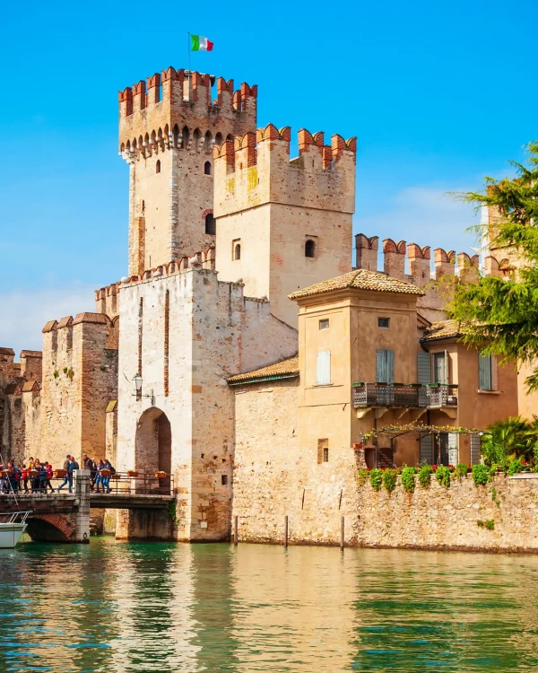 Castello medievale di Sirmione con bandiera italiana sul lago di Garda.